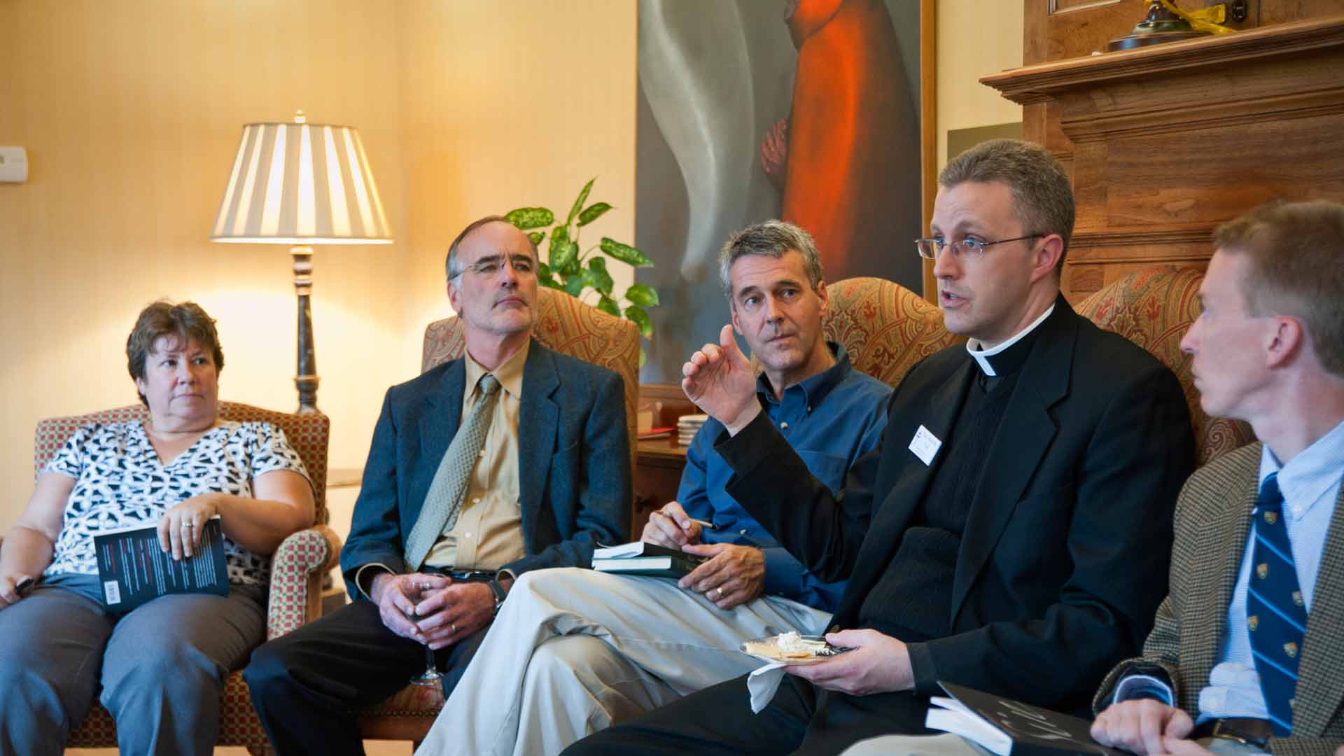 Priest speaking to group of staff members
