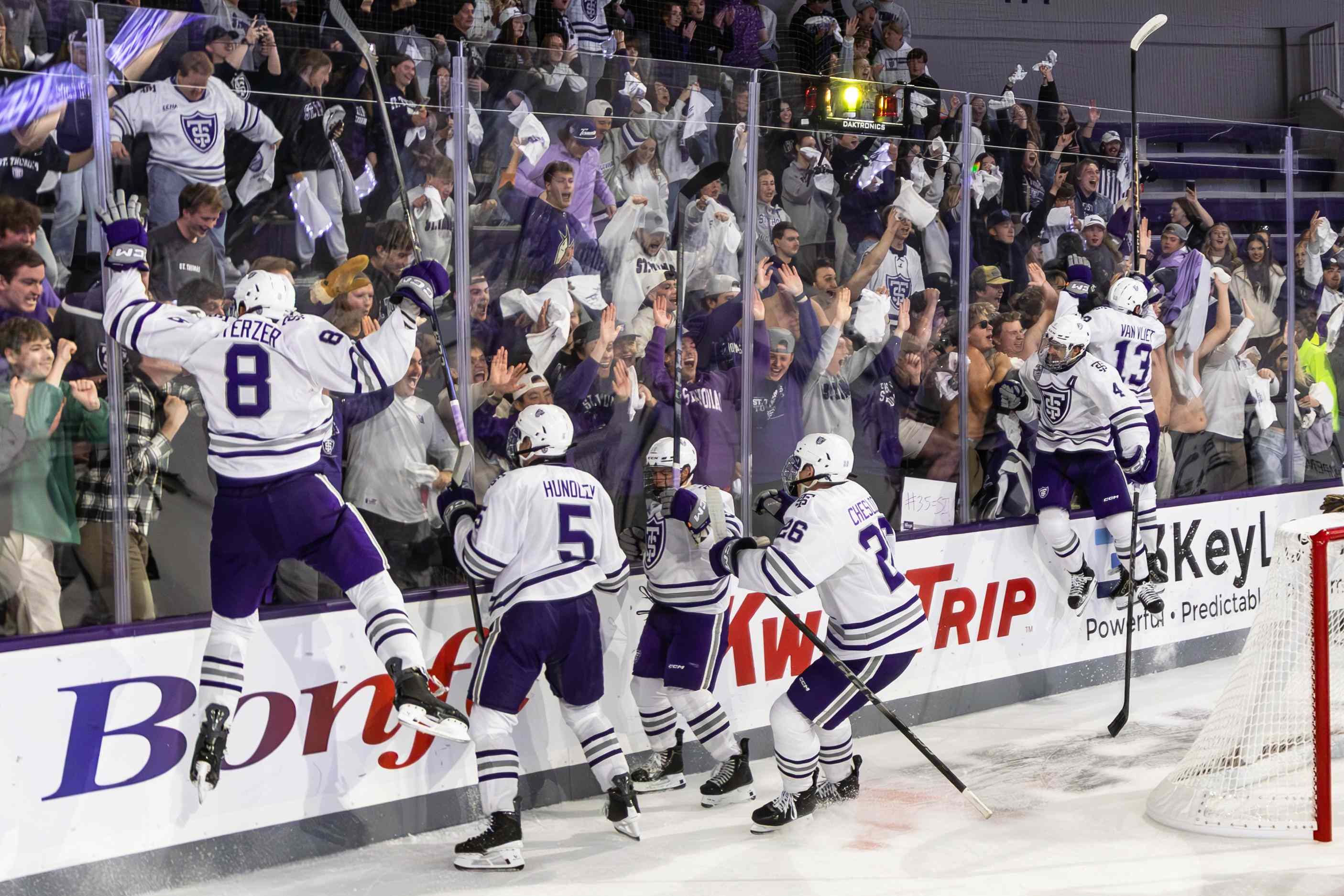 hockey players leap against the arena glass in celebration of a goal