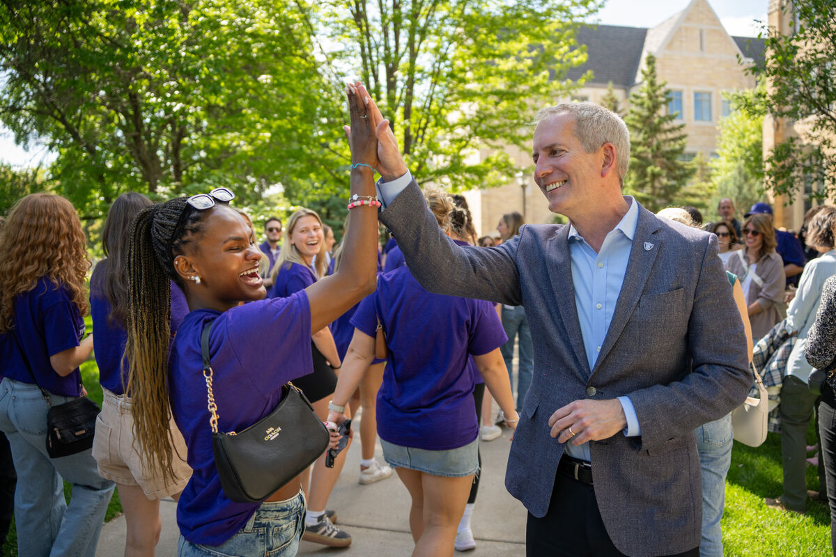President Rob Vischer high fiving student outside on campus.
