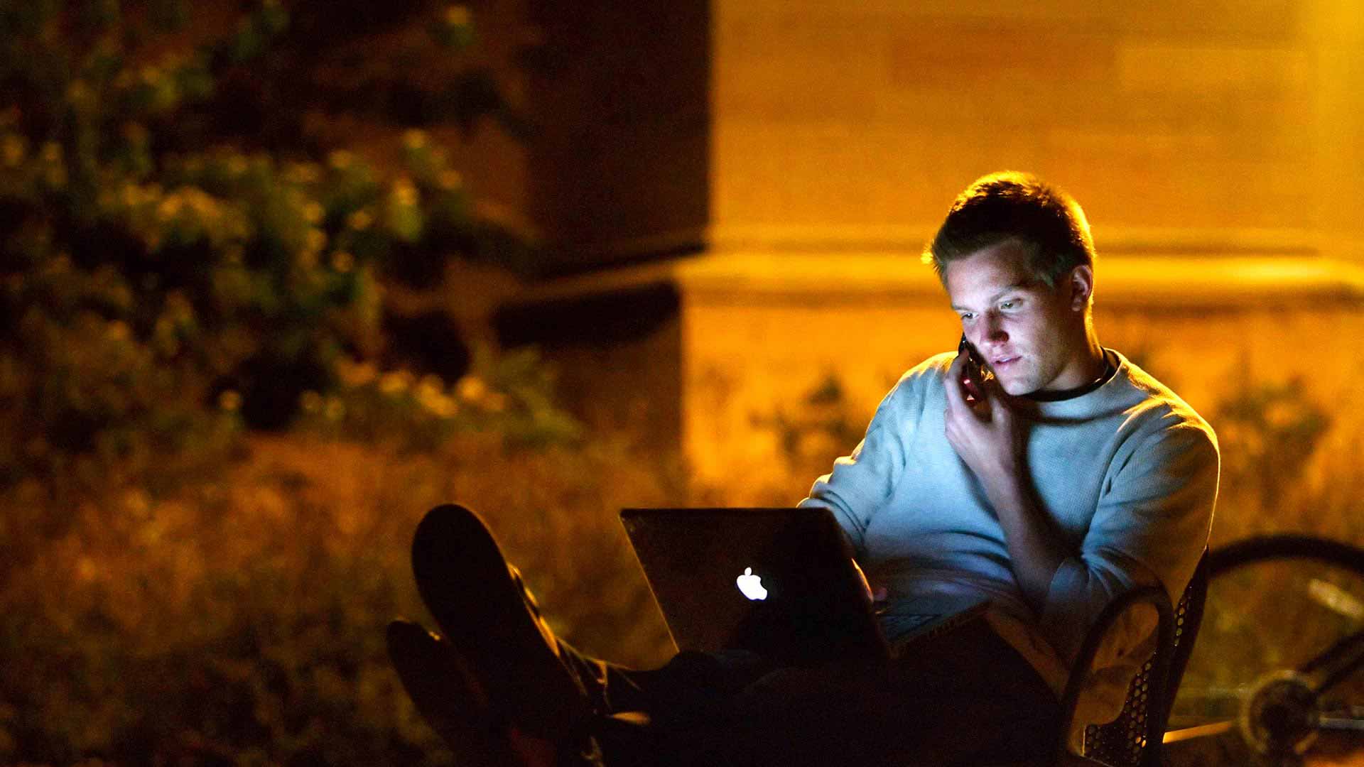St. Thomas alum talks on his phone and works on his laptop.