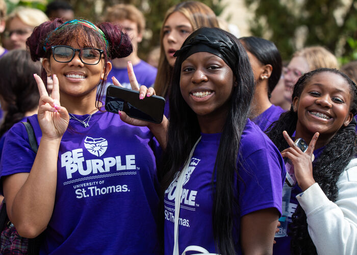 students wearing purple shirts smile at the camera