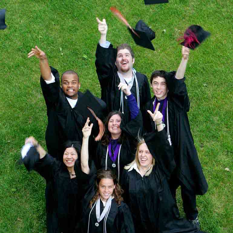 group of graduates throw caps in the air