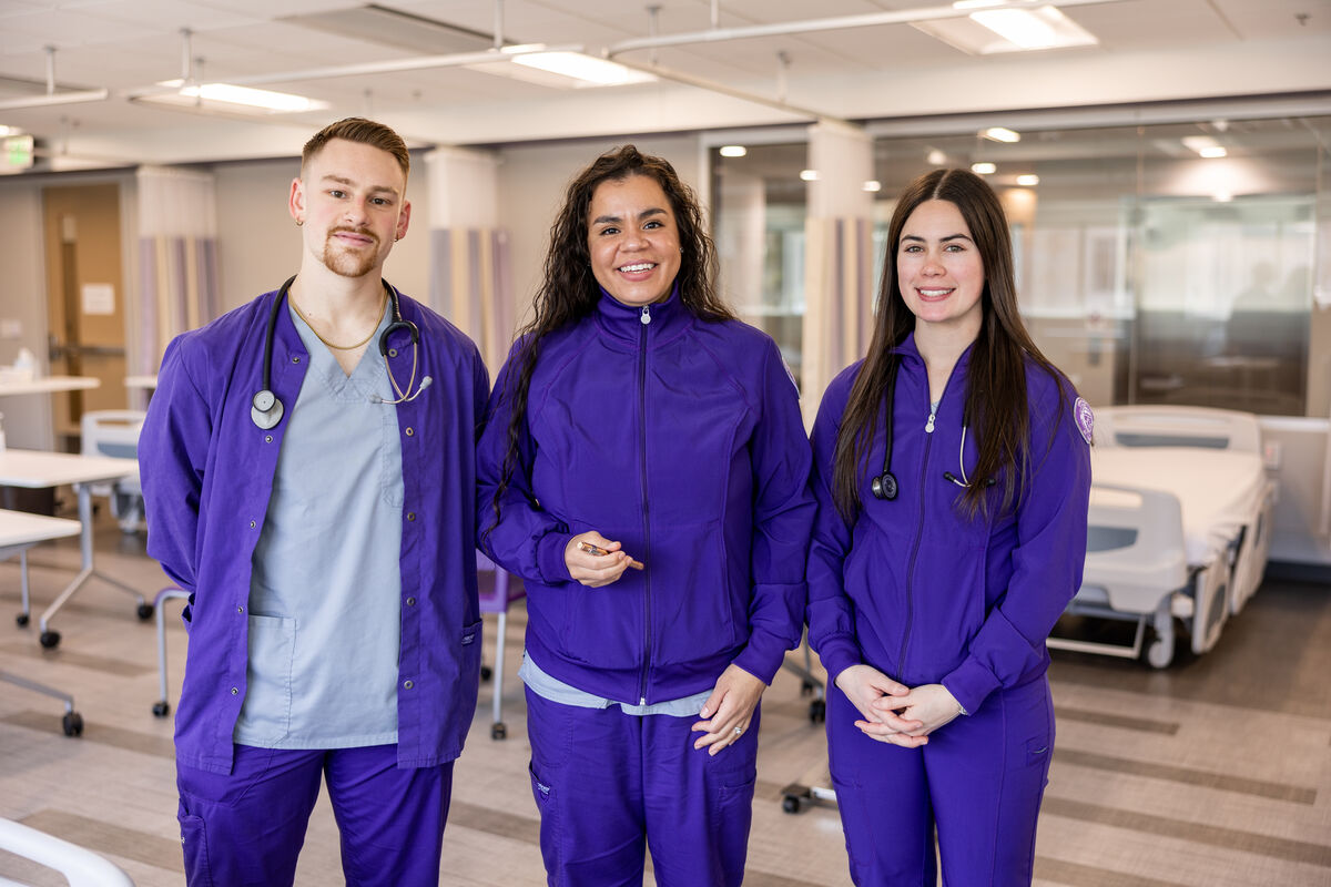 Three nursing students standing together in a practice emergency room.