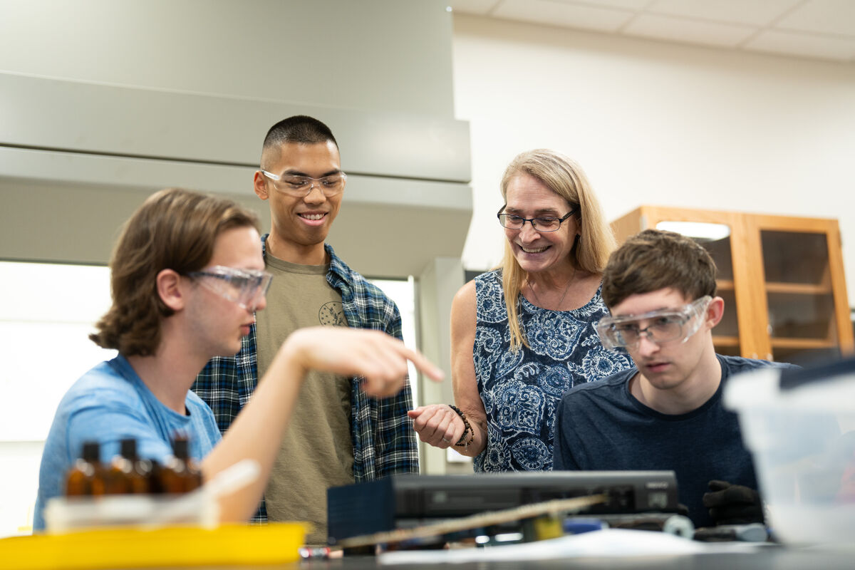 Engineering professor and three students looking at their work.