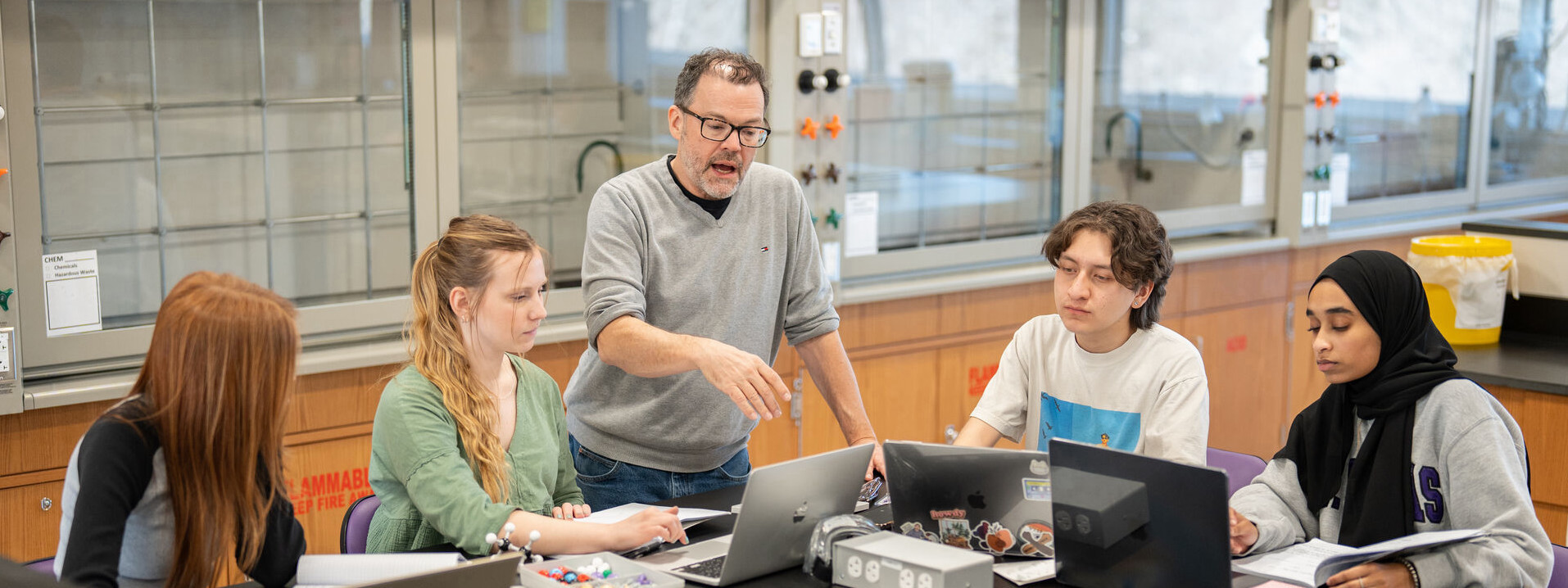 Chemistry professor teaching four students in a classroom.
