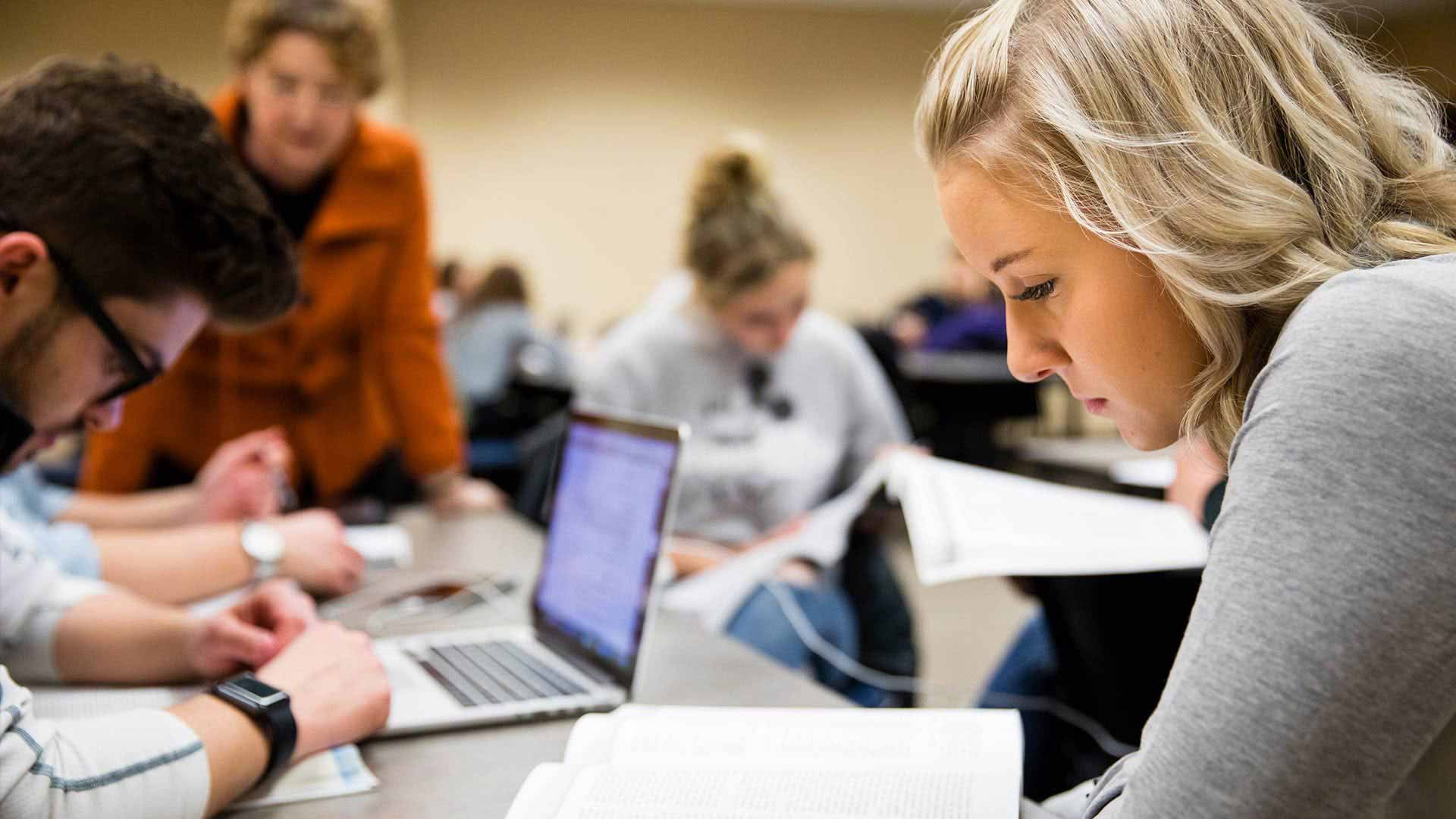 Students study over books in a classroom