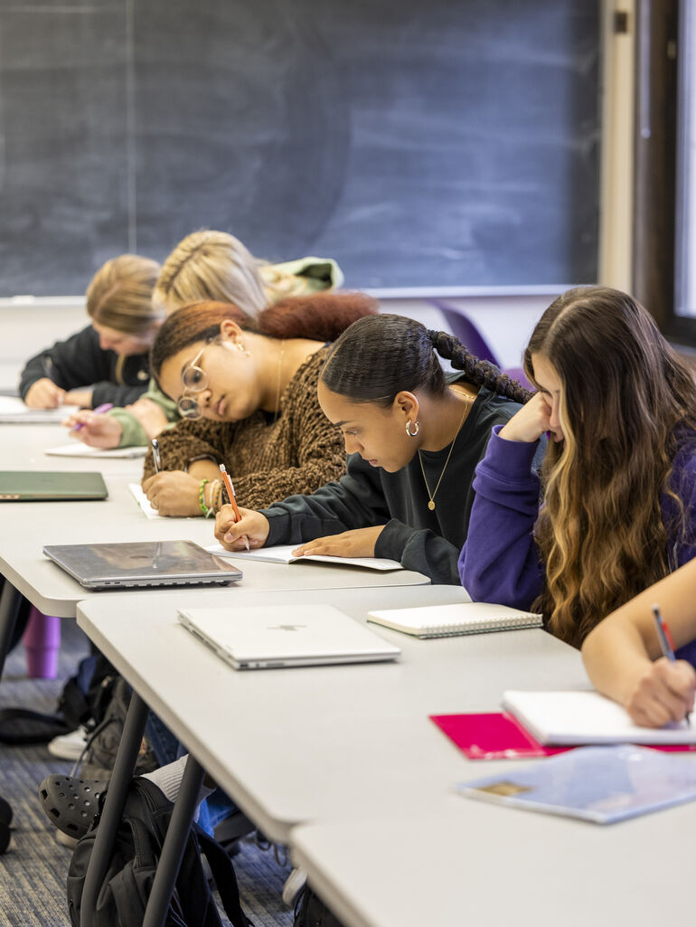 four female students writing in an English class
