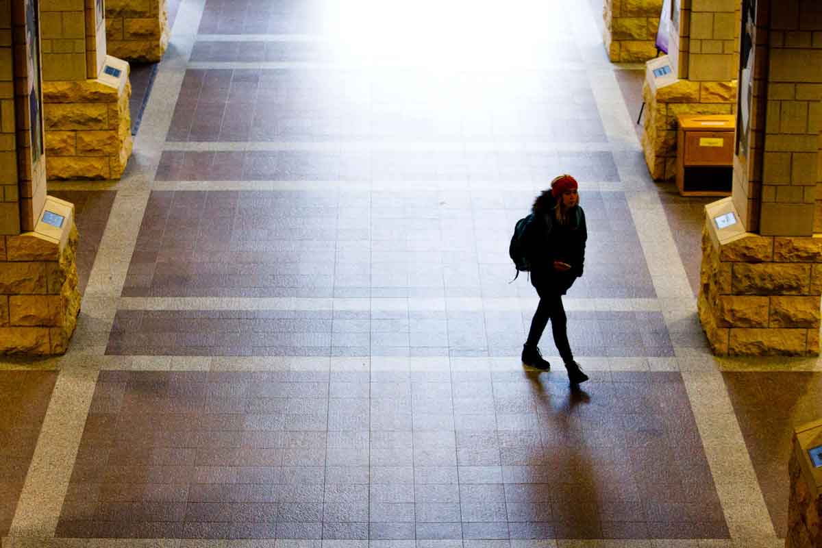 Female walks through Terrence Murphy Hall atrium.