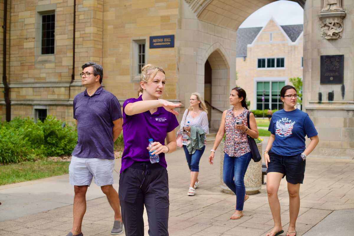 student tour guide shows a group of visitors around campus