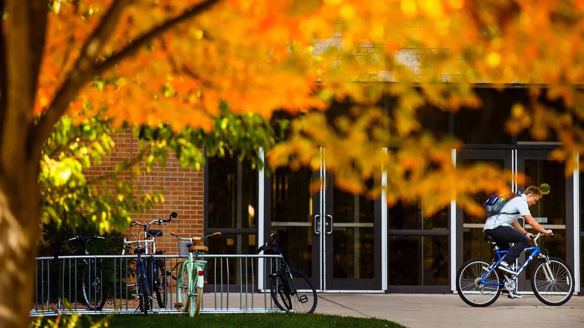 A student hops on his bike outside the entrance to Koch Commons October 11, 2016. 