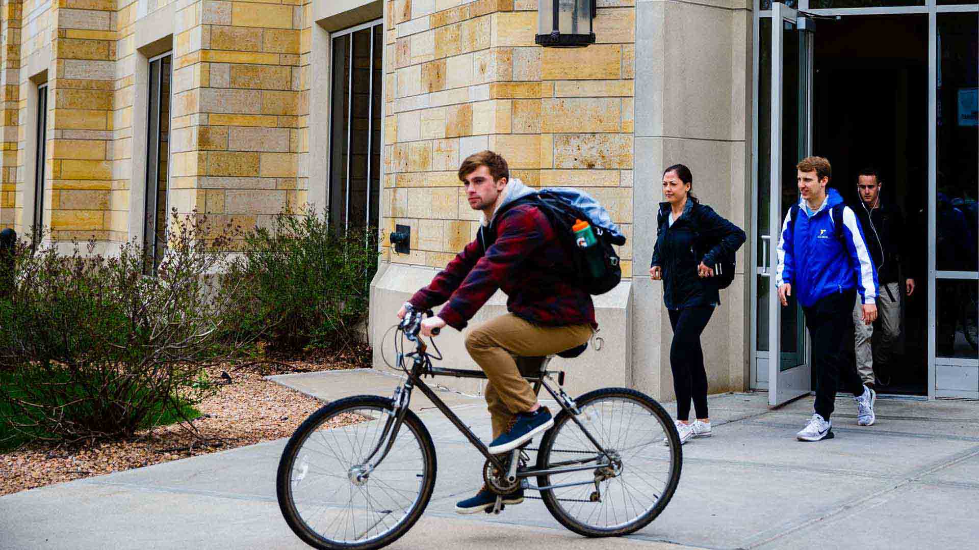 Several students exit McNeely hall by foot and on bicycle.