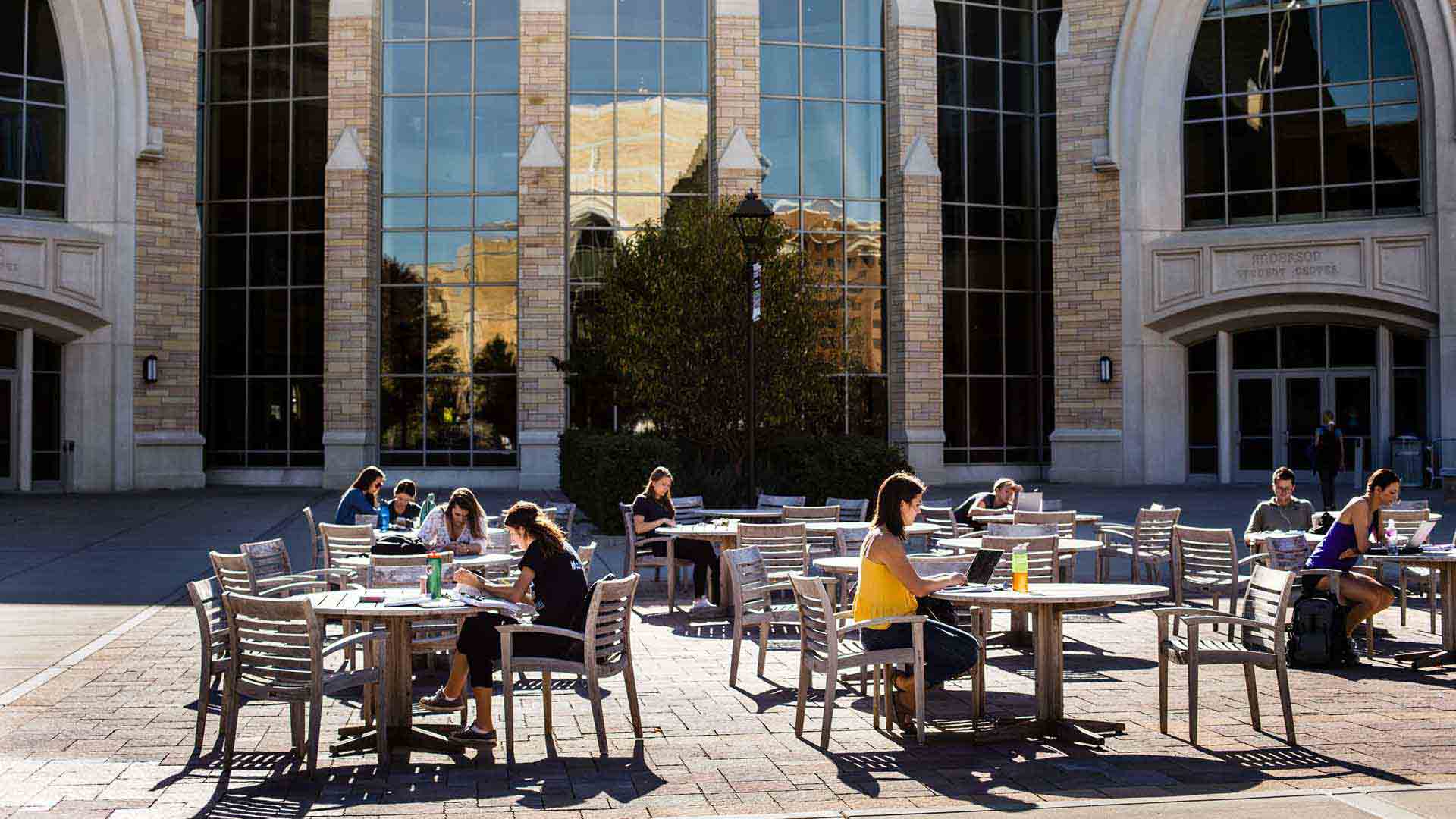 Students study at tables outside of Anderson Hall in the autumn.