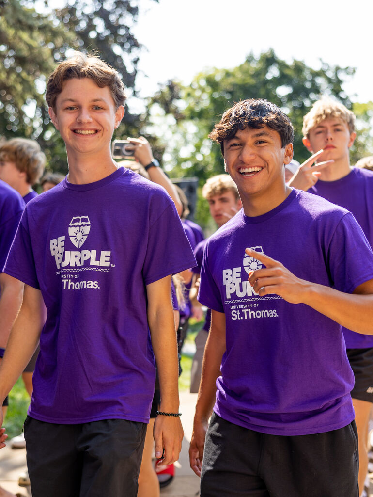 Two male students smiling during march through the arches