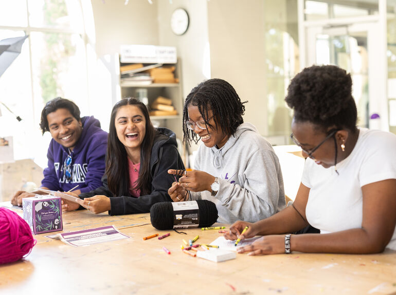 Four international students sitting together at a table doing crafts.