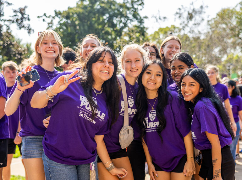 Group of students in purple shirts posing together and smiling.