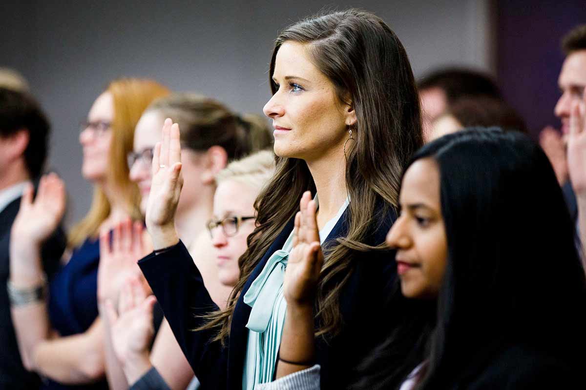 Law students raise their hands and take an oath during a swearing in ceremony.