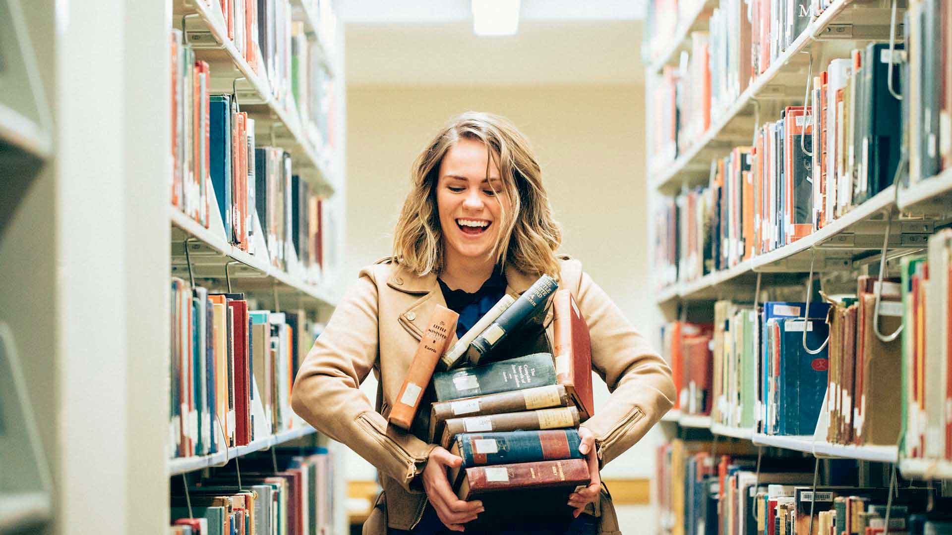   Senior English major Halle Mason poses for a portrait while holding a stack of books in the O'Shaughnessy-Frey Library Center in St. Paul on November 21, 2017. Mason is obsessive about Jane Austen and publishes a popular blog about dating. 