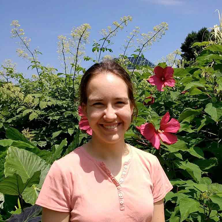 Photo of Erin Buchmann in front of flower bush.