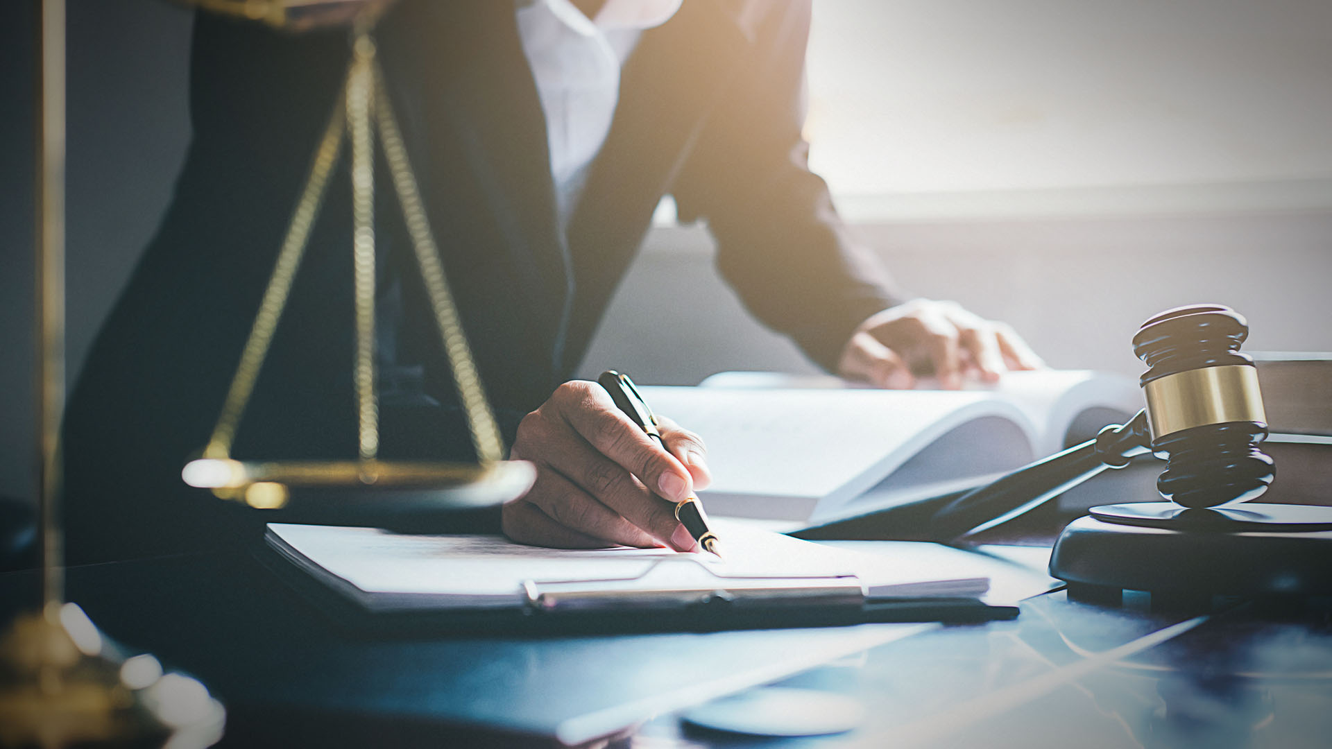 Scales of law in front of a person taking notes from a book