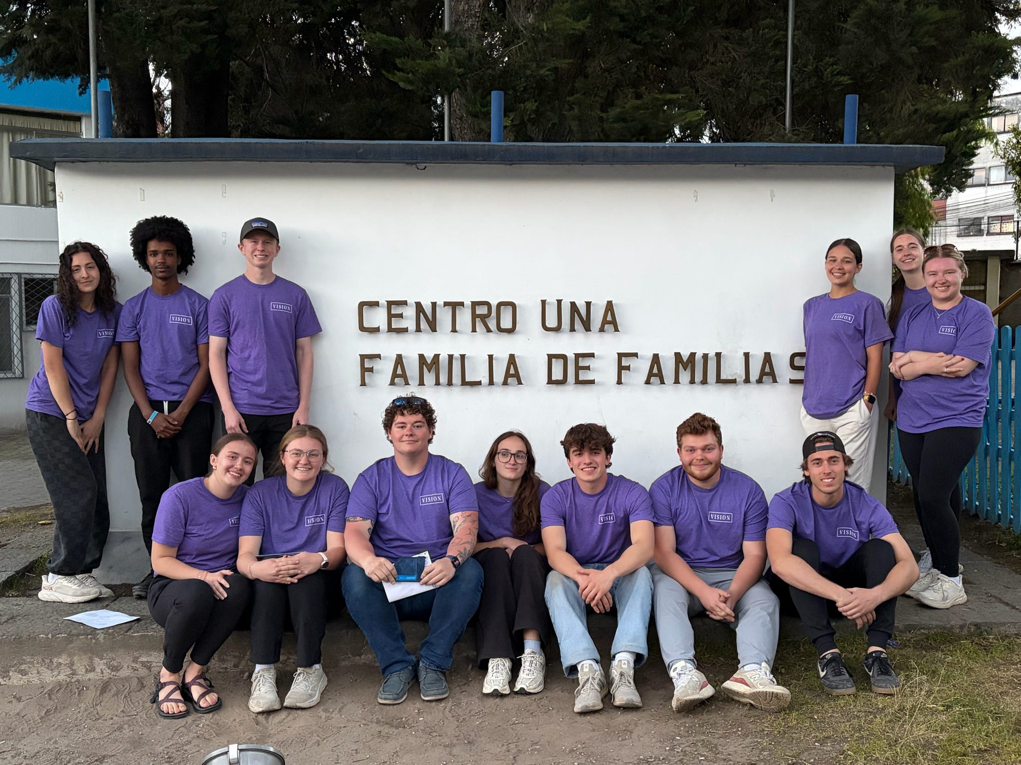 Students in St. Thomas tshirts standing in front of sign for Centro de Familia de Familias