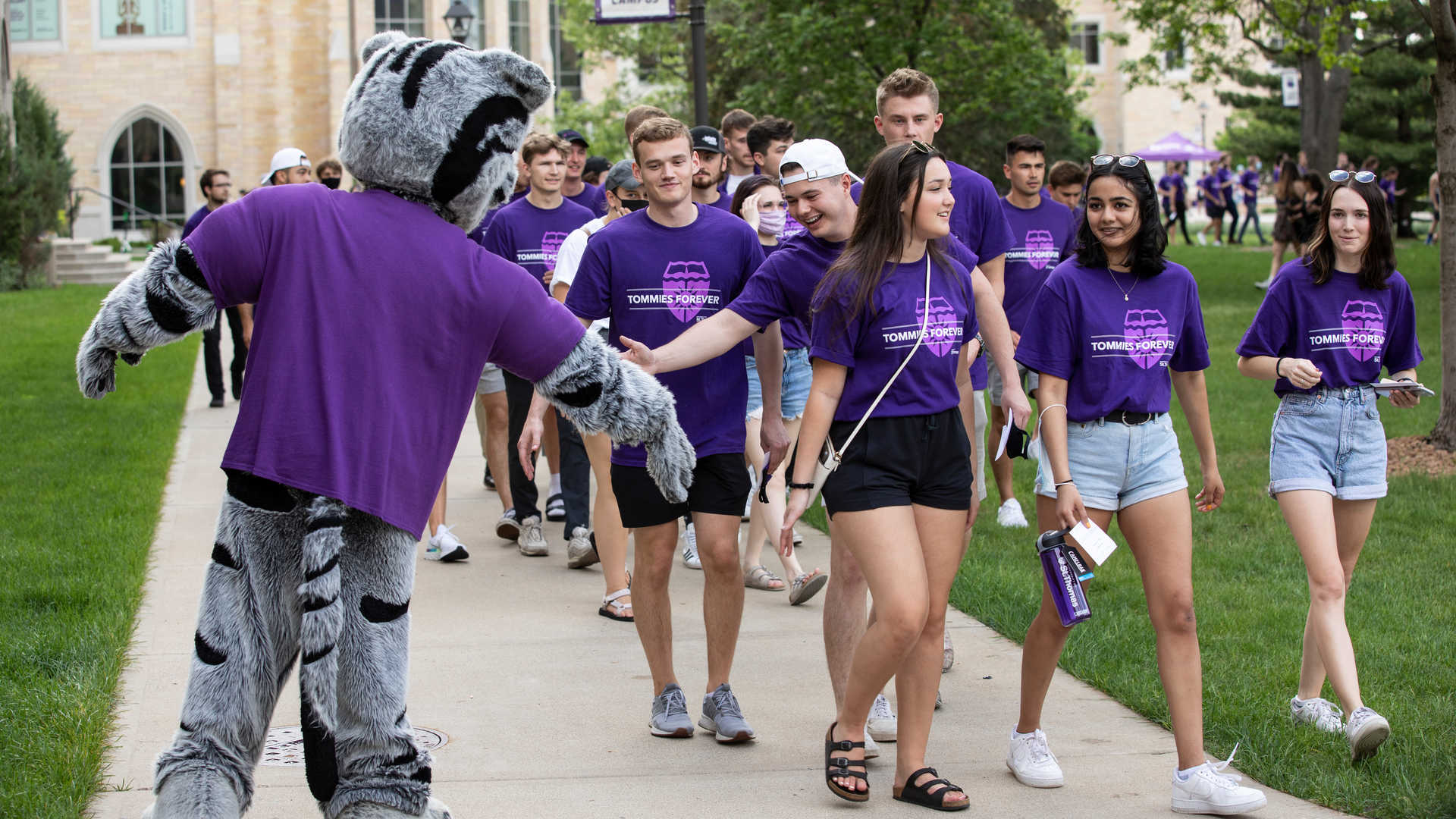 students are greeting the mascot tommie 