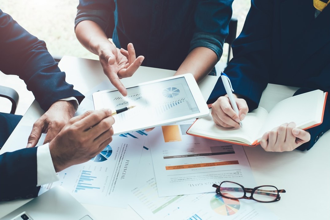 hands of working colleagues hover over graphs and paperwork