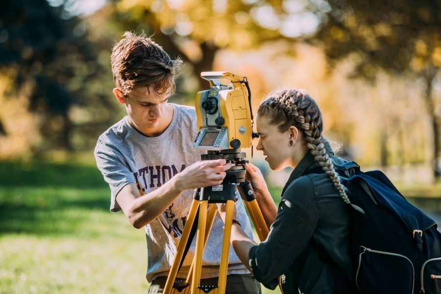 St. Thomas civil engineering student use surveying equipment on the campus grounds.