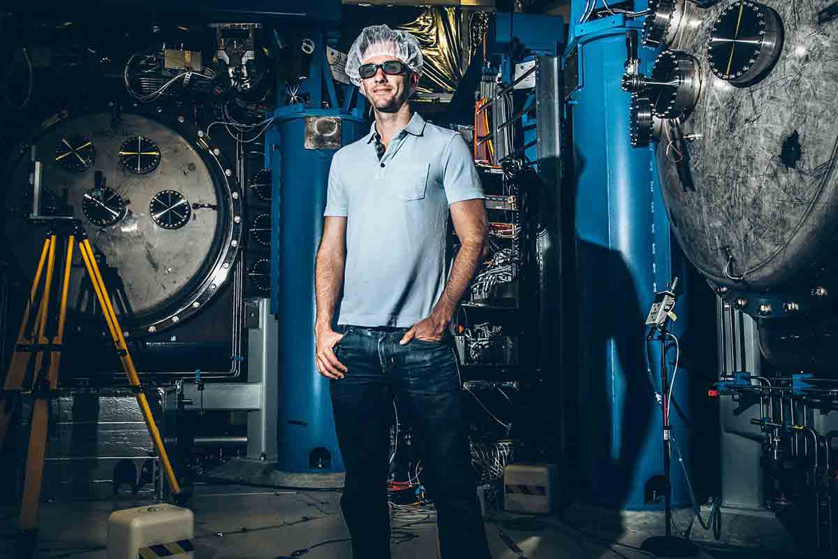 Professor stands in a workshop that houses a laser observatory.
