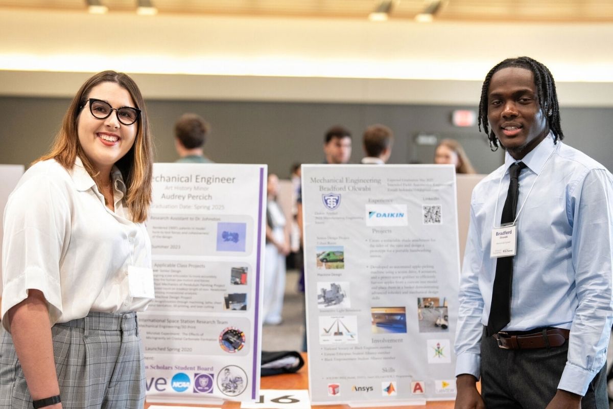 St. Thomas engineering students stand beside their presentation boards at a Meet the Engineers event.