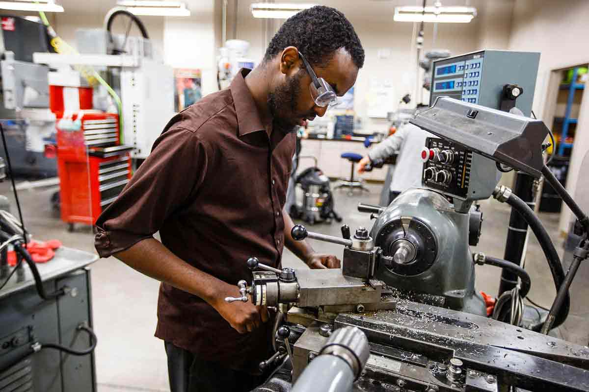 A student operates a metal shaping tool.