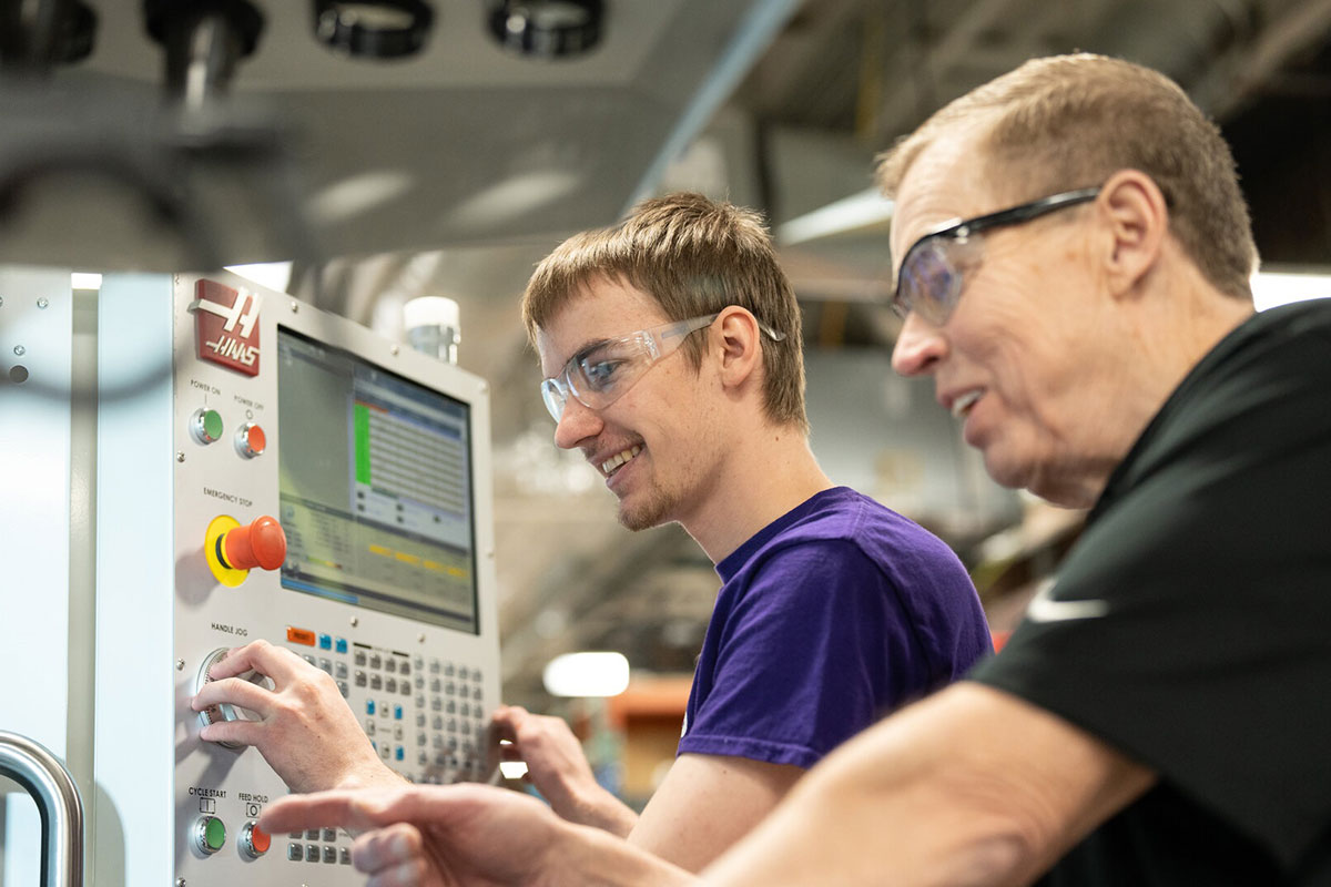 Student manipulates the controls on a CNC machine.