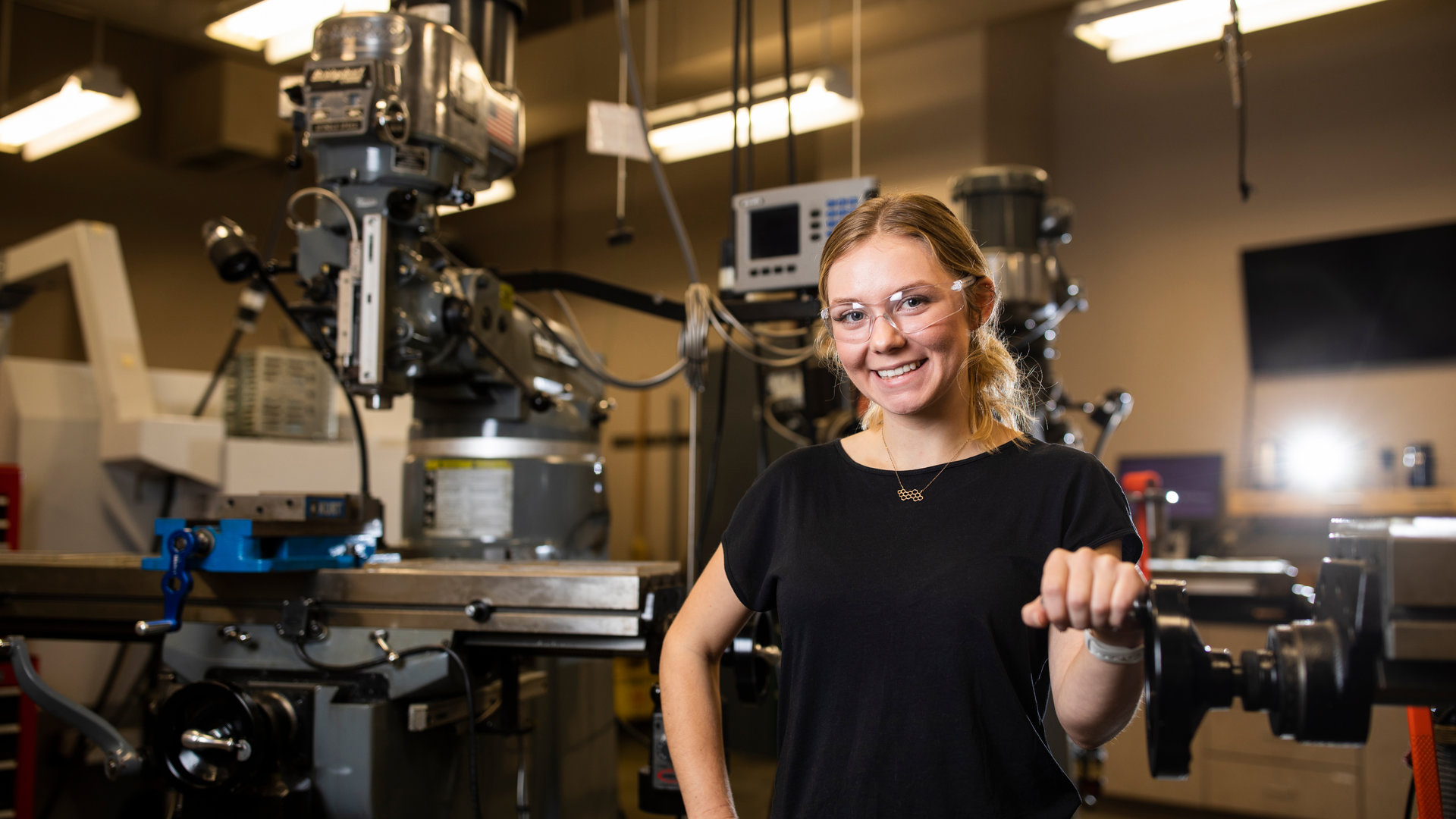 A mechanical engineering student poses in the machine shop.