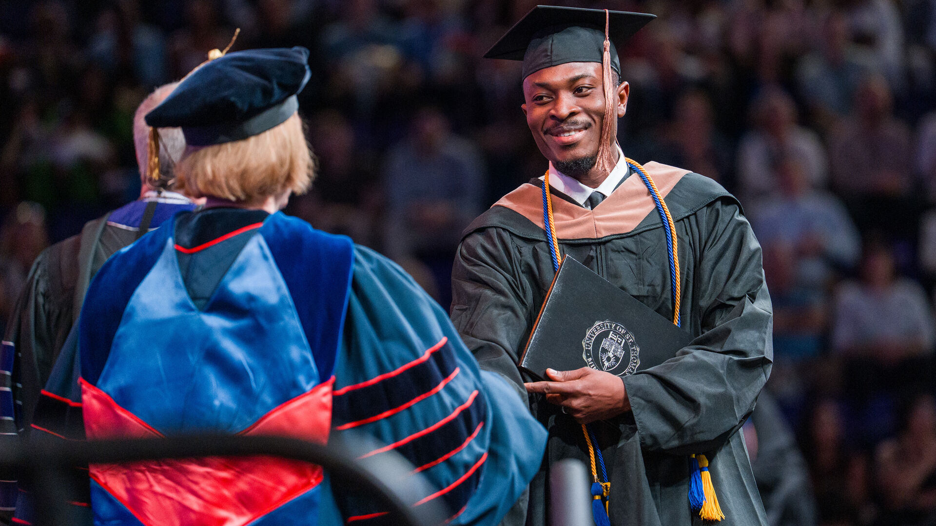 Graduate crossing stage and shaking hands with President Vischer