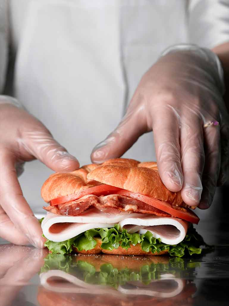 Sandwich being served by someone wearing gloves