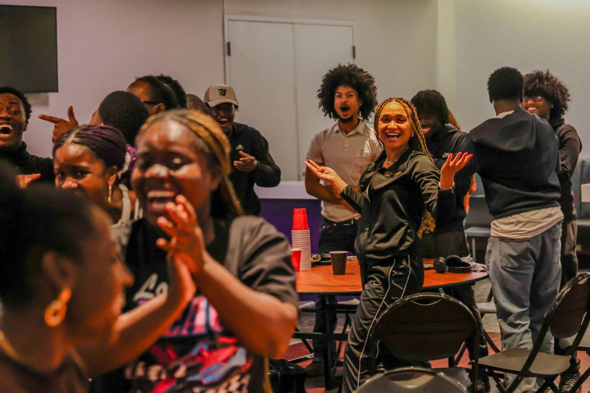 Group of students standing and laughing around tables after playing a game