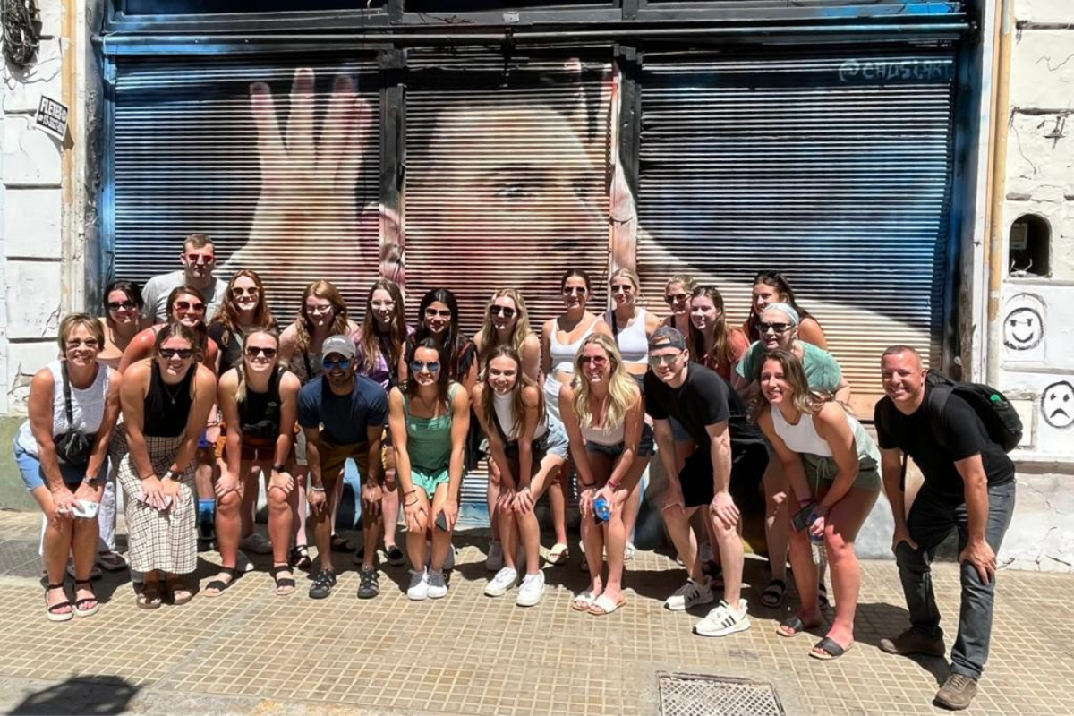 students gathered in front of Messi street art