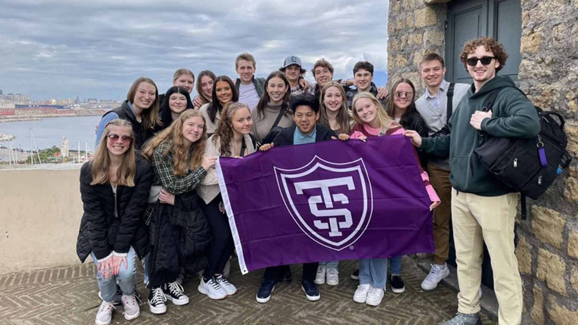 Group of students posing with St. Thomas flag