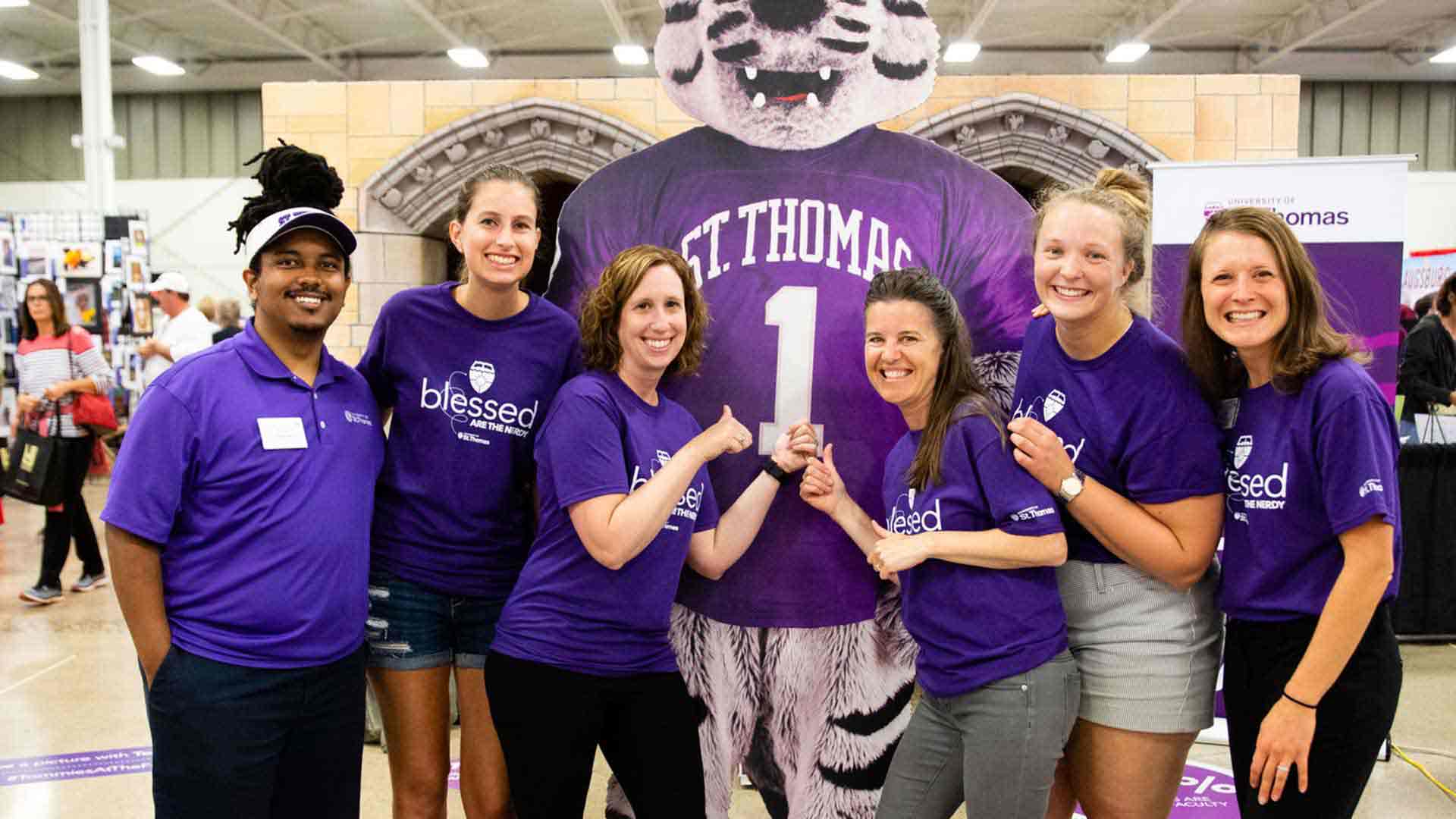 Staffers and student works pose with a cutout of Tommie the mascot at the Minnesota State Fair.