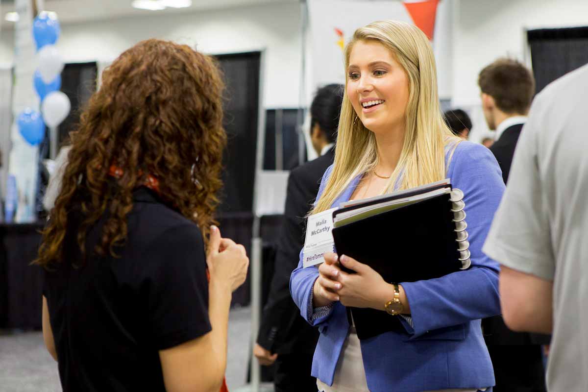 A student speaks with a recruiter at an employment event.