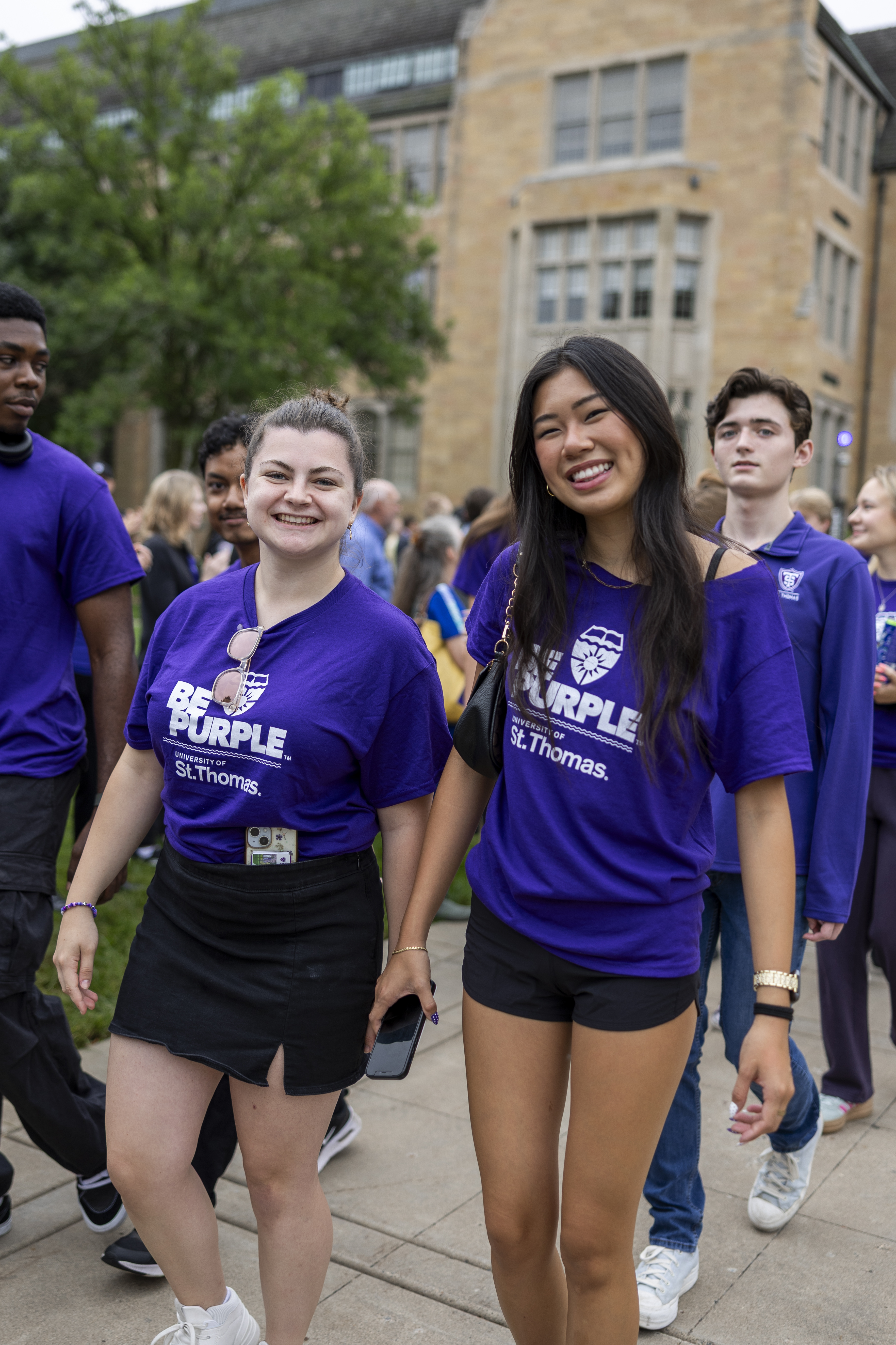 Students walking through the Arches on campus and smiling.