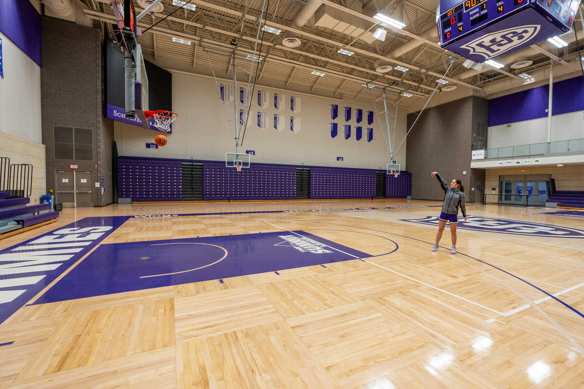 student shoots baskets in the indoor basketball court in aarc