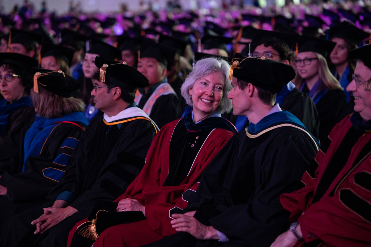 faculty chat while seated at commencement