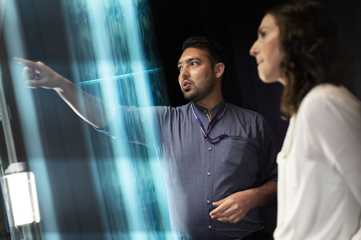 man and woman discuss something on a large clear-glass screen