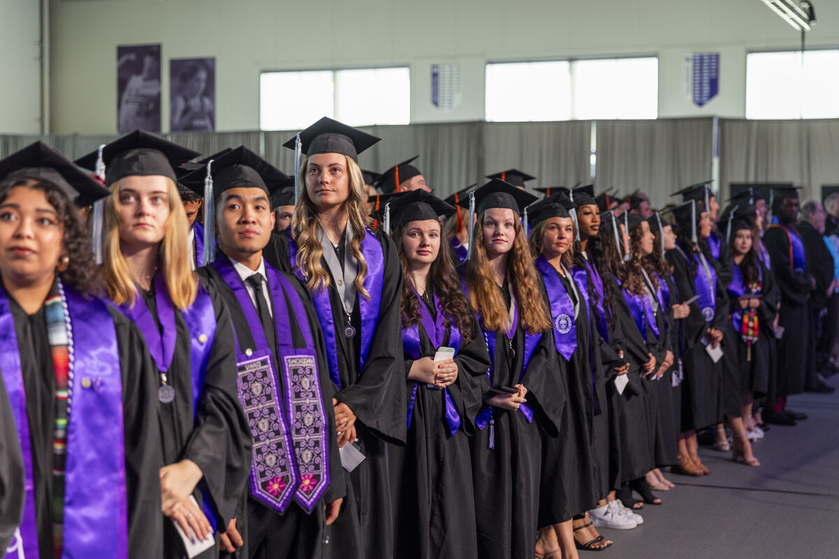 students in a line in commencement caps and gowns
