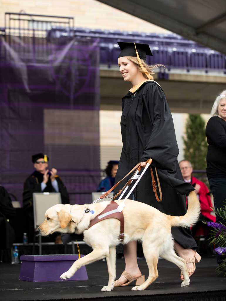 Student at graduation with a service dog.