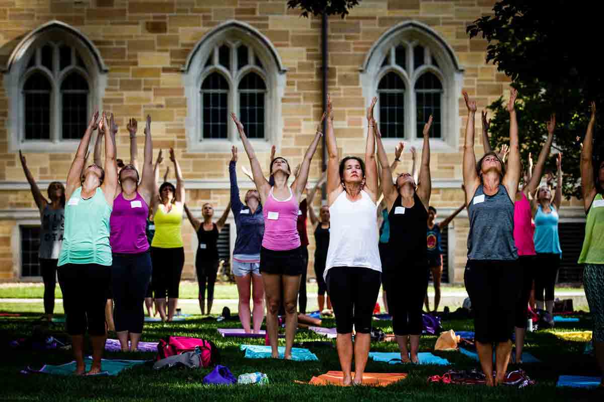 a group of women doing a yoga pose outside on campus