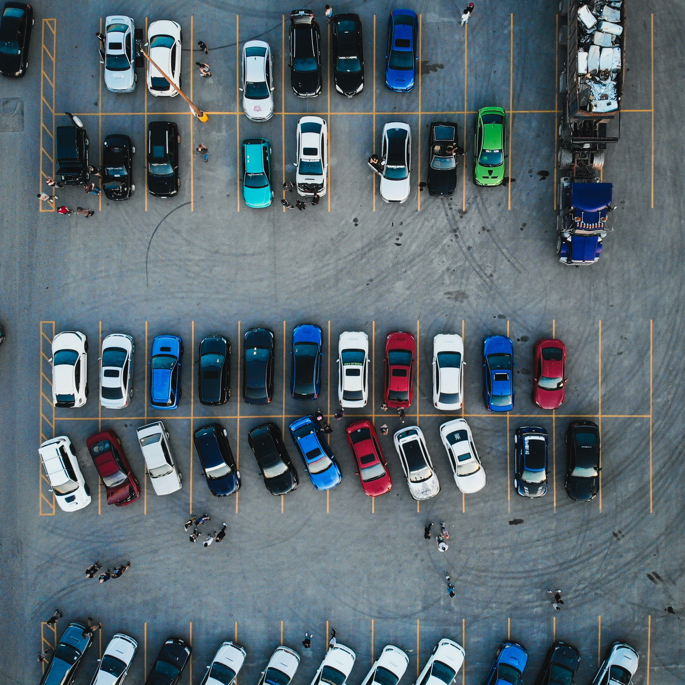 a parking lot with vehicles and people.