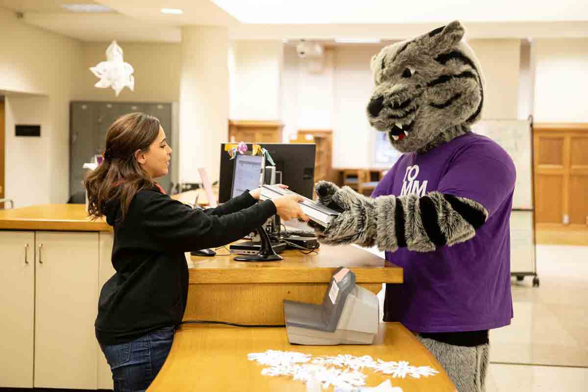 tommie mascot checks out books at the library