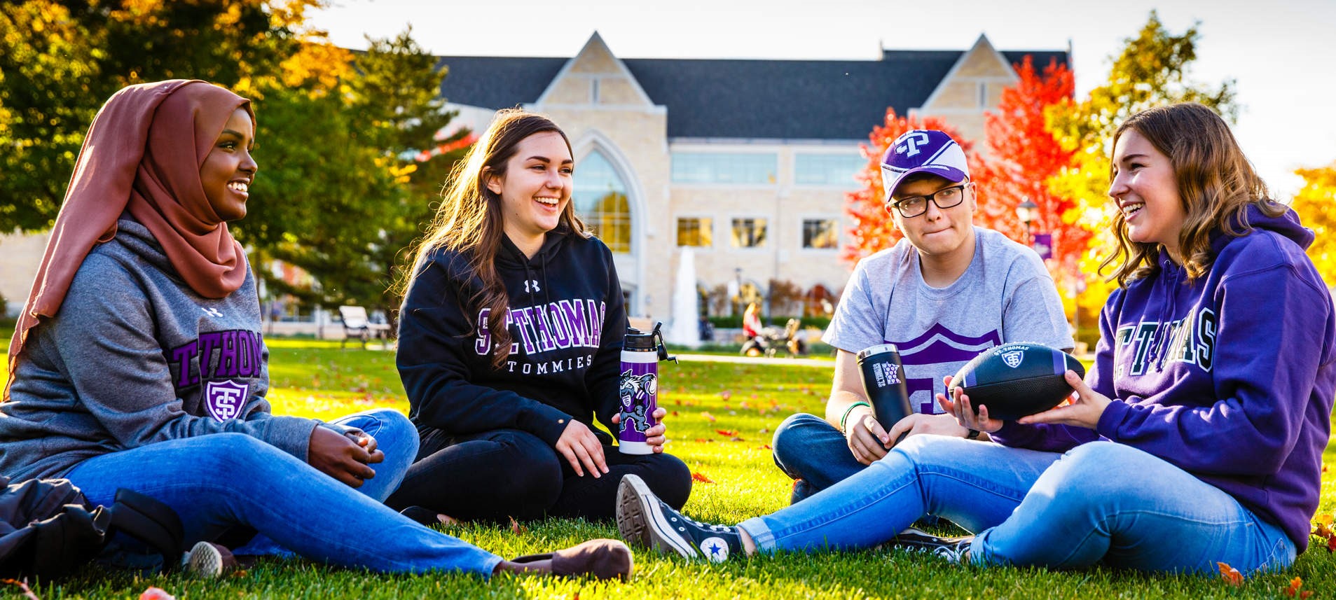 Students sitting on the upper quad in Tommie gear, smiling