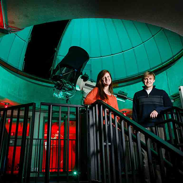 Two physics students pose for a portrait in the University of St. Thomas Observatory.